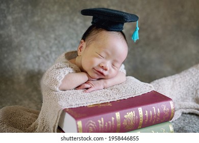 Cute Clever Baby In Black Graduation Cap Sleeping On Big Books With Smiling On Blur Background