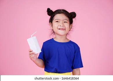 Cute Confident Asian Little Child Girl Is Drinking A Milk Box Isolated On Pink Background