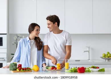 Cute couple cooking in kitchen, man chopping vegetables. Healthy food concept. - Powered by Shutterstock