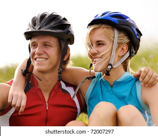 Cute couple with cycling helmets laugh together and have fun outdoors