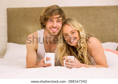 Cute couple having coffee in their bed in the bedroom
