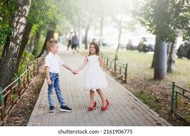 Cute Couple Kids Boy And Girl Hold Hands On Walk In Summer. Girl Child In High Heels, Kids Play Date