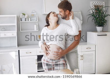 Cute couple in a kitchen. Lady in a white shirt. pregnant woman.