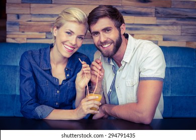 Cute couple on a date sharing a glass of orange juice at the cafe - Powered by Shutterstock