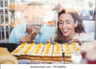 Cute couple pointing pastries through the glass in the bakery store - Powered by Shutterstock