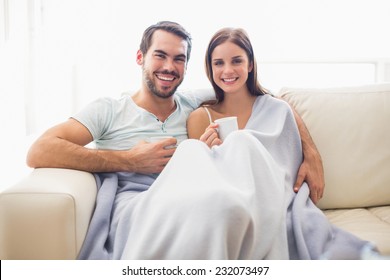 Cute Couple Relaxing On Couch Under Blanket At Home In The Living Room