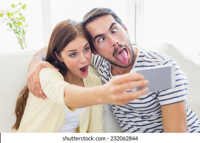 Cute couple taking a selfie on couch at home in the living room - Powered by Shutterstock