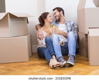 Cute couple toasting with champagne on floor in their new home