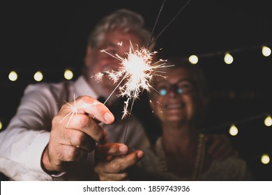 cute couple of two senior in love together the new year night playing with the sparklers in their hand near of the camera