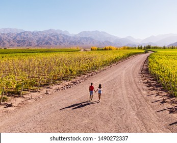 Cute Couple walking down path leading towards nature, view of mountain background, blue clear sky and green vineyards. Perspective, goal, outdoors, nature, travel concepts. Mendoza, Argentina - Powered by Shutterstock