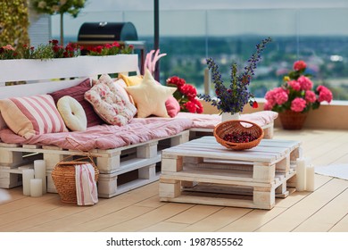 süße, gemütliche Palettenmöbel mit bunten Kissen auf der Sommerterrasse, Salonbereich im Freien