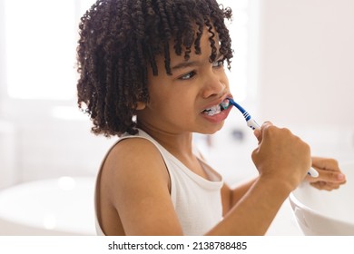 Cute Curly Hair Hispanic Boy Brushing Teeth In Bathroom At Home. Unaltered, Childhood, Hygiene And Routine Concept.