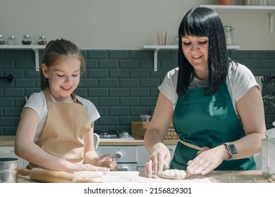 Cute daughter learning kneading dough with hands helping mom in modern kitchen, happy family adult mother and little child girl prepare cookies biscuit having fun cooking together at home