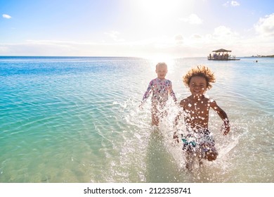 A Cute diverse boy and little girl running and splashing together in the Caribbean ocean in the late afternoon while on a family vacation. Running Along the beach - Shutterstock ID 2122358741