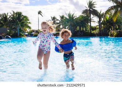 A Cute diverse boy and little girl running and splashing together holding hands in the large swimming pool resort while on a family vacation - Powered by Shutterstock