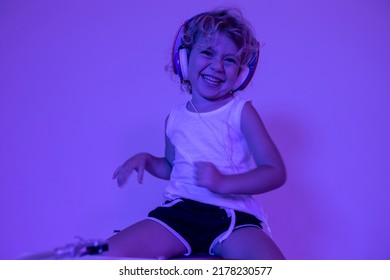 A cute djing small girl with headphones with coloured disco lighting