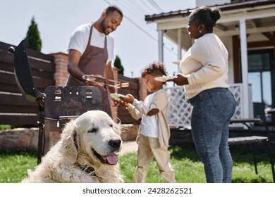 cute dog near african american family having family bbq party on backyard of their house in suburbs - Powered by Shutterstock