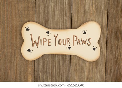 Cute Dog Saying , A Wood Dog Bone On A Weathered Wood Background With Text Wipe Your Paws