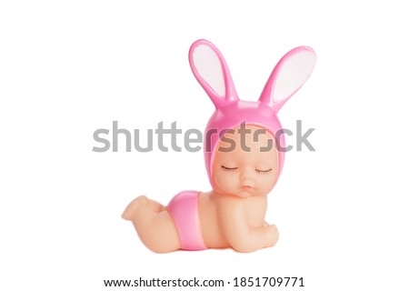A cute doll in pink panties and a hat with bunny ears, with closed eyes. On a white isolated background. An adorable toy for a gift or child's play. Soft focus.
