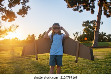 Cute dreamer boy playing with a cardboard airplane on a background of sunset sky. Childhood. Fantasy, imagination. - Shutterstock ID 2124799169