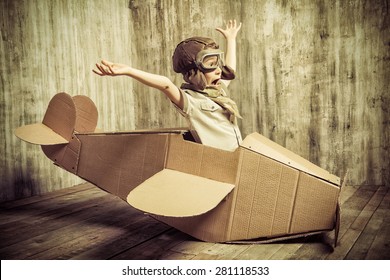Cute dreamer boy playing with a cardboard airplane. Childhood. Fantasy, imagination. Retro style. - Shutterstock ID 281118533