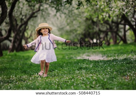 cute dreamy toddler child girl walking in blooming spring garden, celebrating easter outdoor