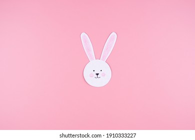 Cute Easter Bunny Face made of paper, on a pink background. Minimalistic concept.