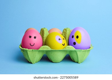 Cute easter eggs with funny faces in green box isolated on light blue background. Happy easter concept. Painted Easter eggs. - Shutterstock ID 2275005589