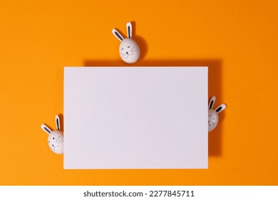 cute easter eggs with rabbit ears and blank card, above view