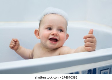 Cute Ecstatic Baby Boy Enjoying Bath And Showing Thumb Up.