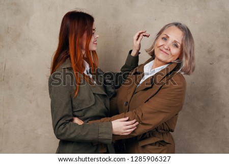Cute elderly woman in a coat next to her daughter hugging
