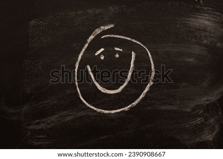 Cute emoticon drawn on a black chalkboard with a smile from ear to ear.