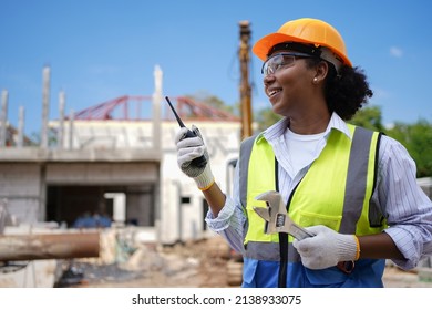 Cute Face Female Engineer Wearing A Hard Hat Vest Walkie-talkie Wrench.a Young Woman With Black Skin Is Working Happily.working Safely Construction Site Management The Back Is  Of The Construction.