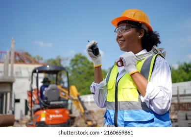 Cute Face Female Engineer Wearing A Hard Hat Vest Walkie-talkie Wrench.a Young Woman With Black Skin Is Working Happily.working Safely Construction Site Management The Back Is Of The Construction.