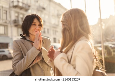 Cute Fair-skinned Adult Brunette Lady Is Touched Looking At Blonde While Standing Outdoors. Old Acquaintances Are Happy To Meet Each Other On Warm Day. People And Free Time Concept