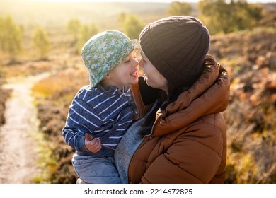 Cute Family Portrait With Mother And Son Playing And Cuddling - Happy Authentic Moment On A Sunny Autumn Day Outdoors