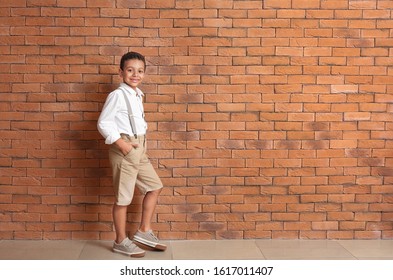 Cute fashionable African-American boy near brick wall