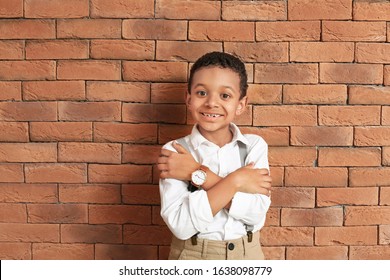 Cute fashionable African-American boy near brick wall