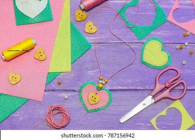 Cute Felt Heart Shape Pendant Necklace. Scissors, Thread, Felt Sheets And Pieces, Buttons, Paper Template On A Wooden Table. Valentines Day Crafts Diy. Sewing For Children. Creative Pastime. Top View