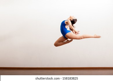 Cute Female Dancer In A Leotard Practicing A Big Jump Of Her Dance Routine In A Studio