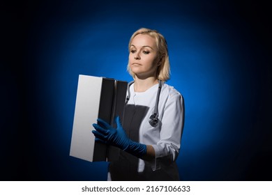 Cute Female Doctor Looks At White Boxes In Her Hands On A Dark Background