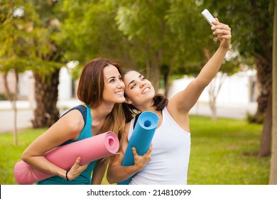 Cute female friends taking a selfie with their smart phone while doing yoga at a park - Powered by Shutterstock