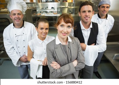 Cute female manager posing with the staff in a modern kitchen