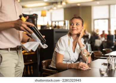 Cute female restaurant customer with wine waiter choosing the right wine for her to go well with the food