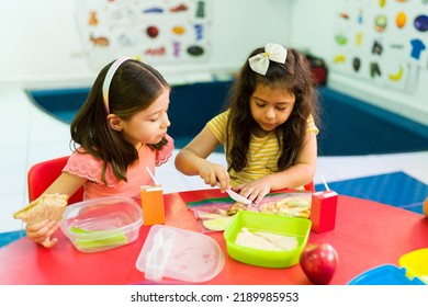 Cute Female Students In Preschool Cutting Their Snack And Learning To Share During Lunch Recess