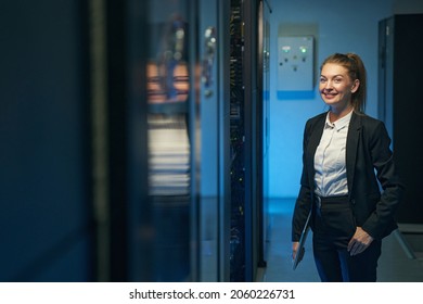 Cute female technician standing in server room