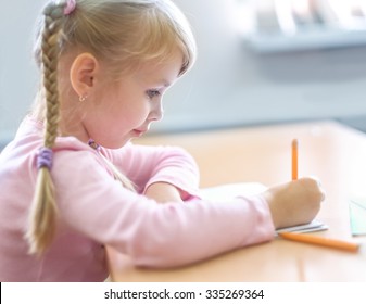 Cute Five Years Old  Blonde Girl Sitting At Classroom And Writing