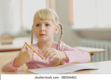 Cute Five Years Old  Blonde Girl Sitting At Classroom And Writing