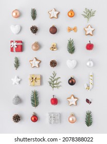 Cute flat lay pattern with Christmas ornaments, baubles, fir, greens, presents, pines, hearts neatly organized in rows. 
Winter holidays concept background 