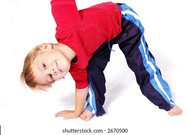 A Cute Four Year Old Boy Wearing Red And Blue Bending Over To Touch His Right Toes.